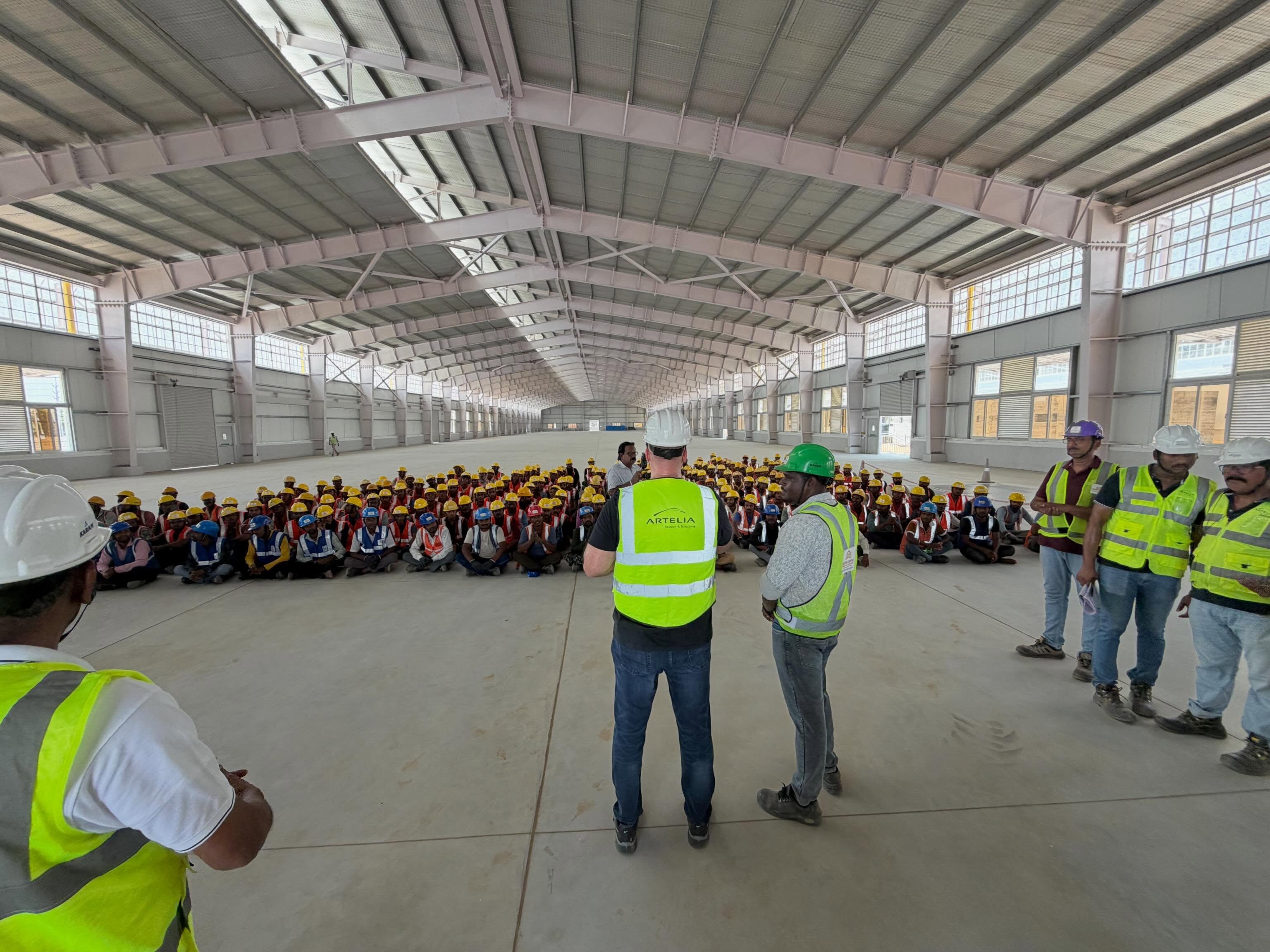 Derek addressing hundreds of workers inside a factory under construction